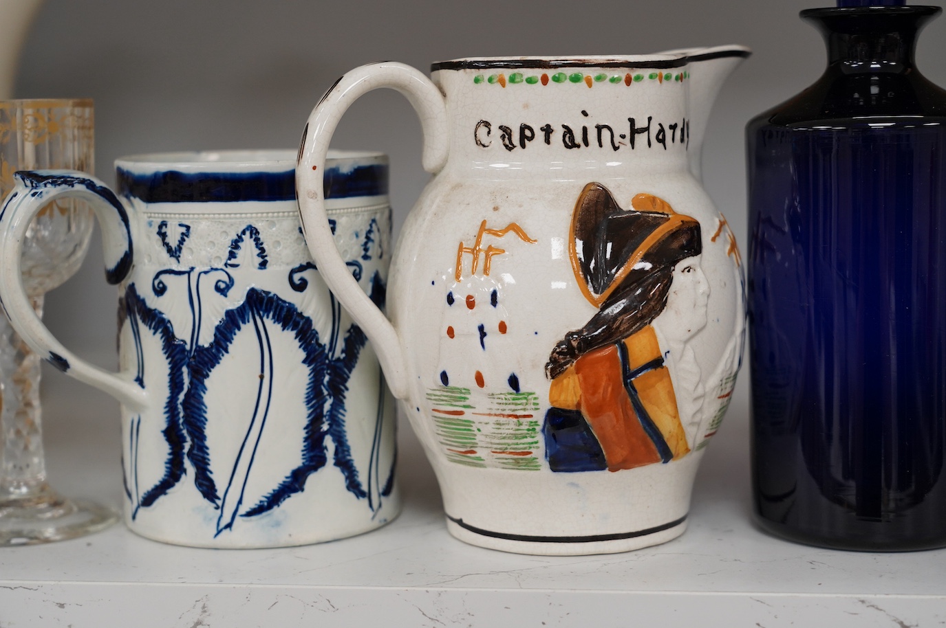 An 18th century pearlware mug, an 18th century Italian maiolica wet drug jar, a faceted wine glass, a commemorative jug and a pair of Bristol blue glass decanters and stoppers, tallest 19cm. Condition - varies